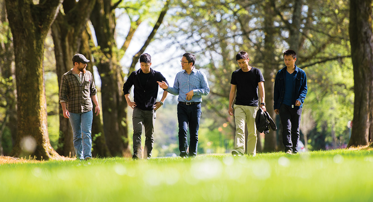 A professor and his students walk together outside.