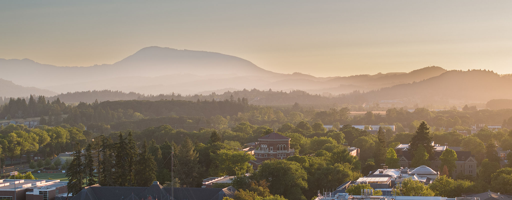 View of Corvallis campus with Marys Peak in the background as the sun sets