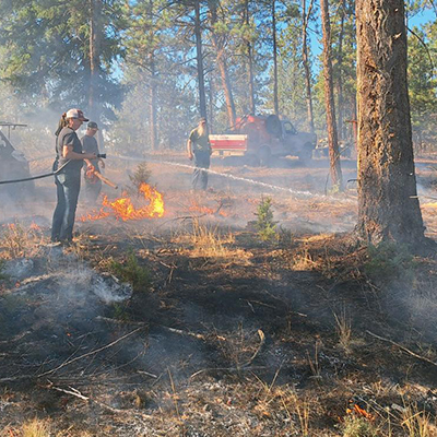 Local landowners spray water to cool down flames around a Douglas-fir tree at the first Southern Blues PBA burn.