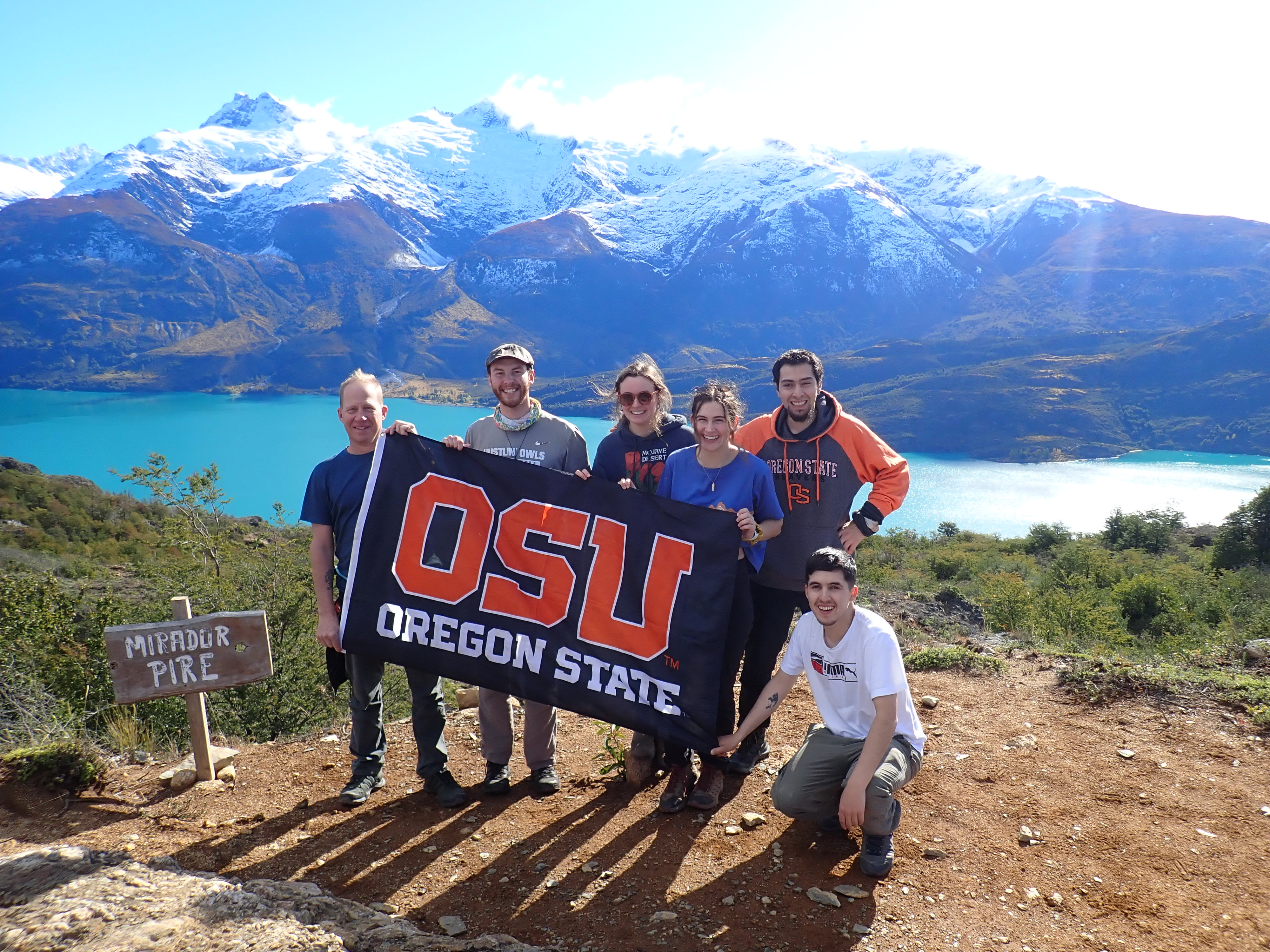 OSU students with flag standing on hill with mountain views