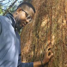 Chukwuemeka Valentine Okolo stands by a big tree