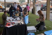 Ariel Cowan (background, middle) and Jenna Deibel (far right) assemble box fan air filters at the Thursday outdoor market in Warm Springs.
